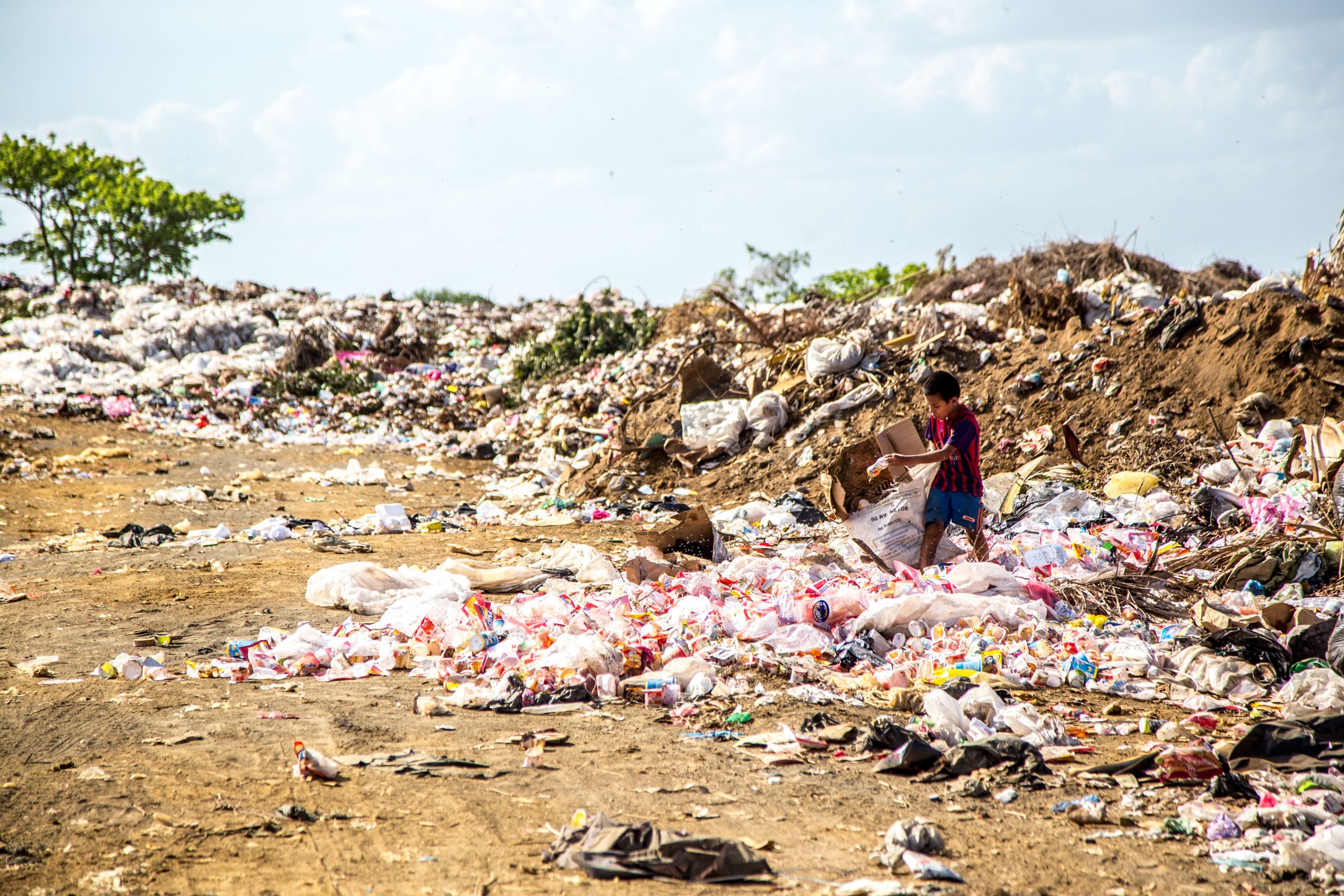 child surrounded by plastic pollution